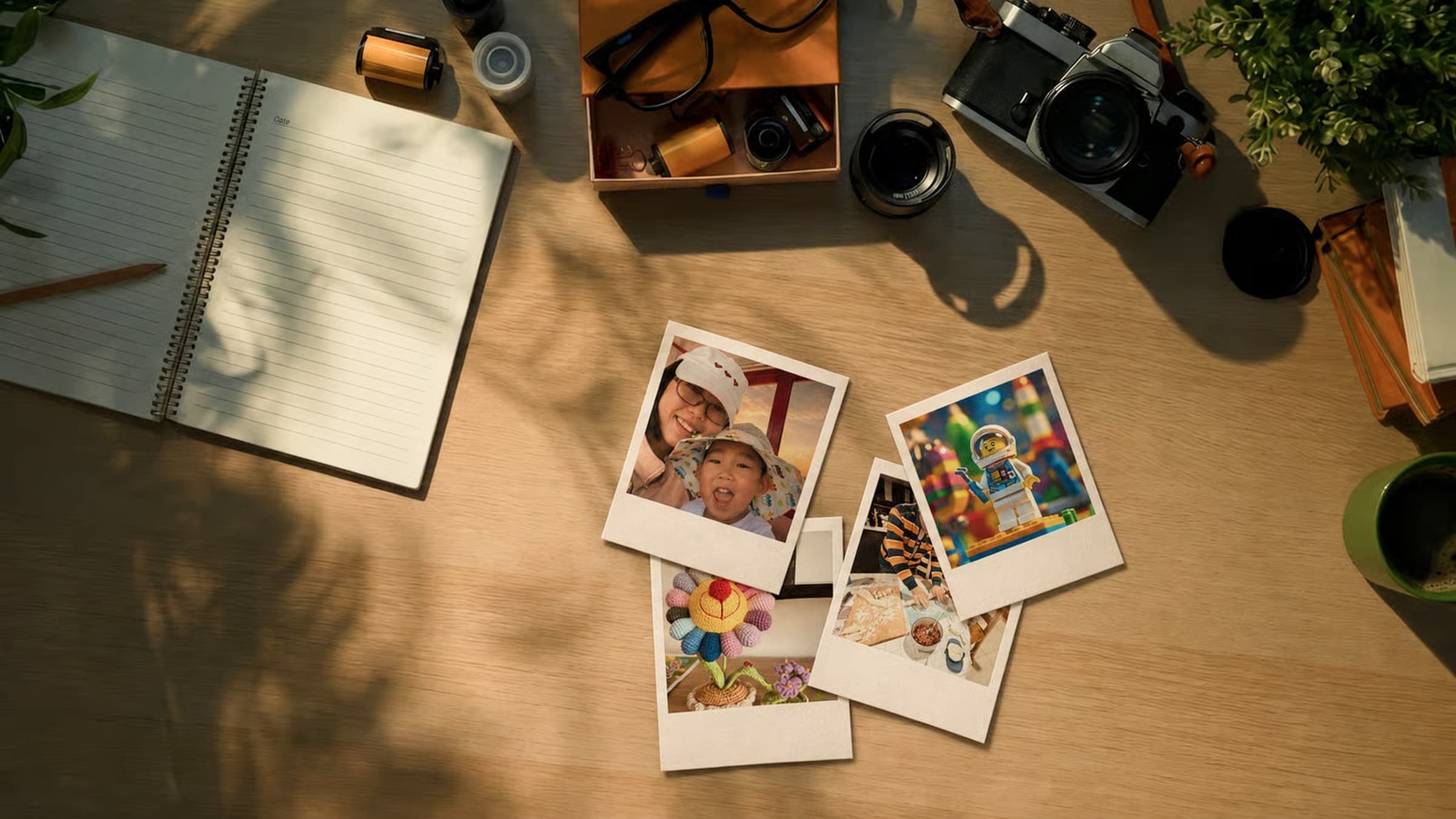 A sunlit desk with a notebook, film camera, and polaroid photos